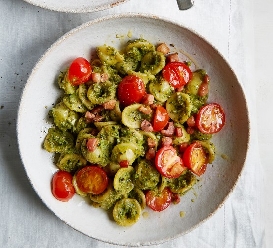 Pesto and pancetta pasta in a bowl with fresh tomatoes
