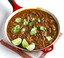 Chilli in pan with herbs and lime wedges