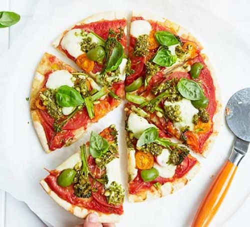 Colourful rainbow pizza topped with cheese and vegetables