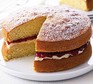 Victoria sponge cake on a plate with a slice cut out