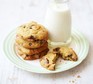 Chocolate chip cookies on a plate with a small glass bottle of milk