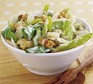 Chicken Caesar salad in a bowl with wooden salad servers