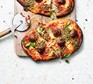 Two sausage & pesto pizzas served on a wooden platter