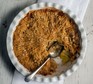 Apple crumble in a round decorative dish with serving spoon