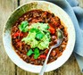 Mexican bean soup with guacamole in a bowl with a spoon