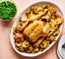 Whole roast chicken with braised roots & peas on a serving platter